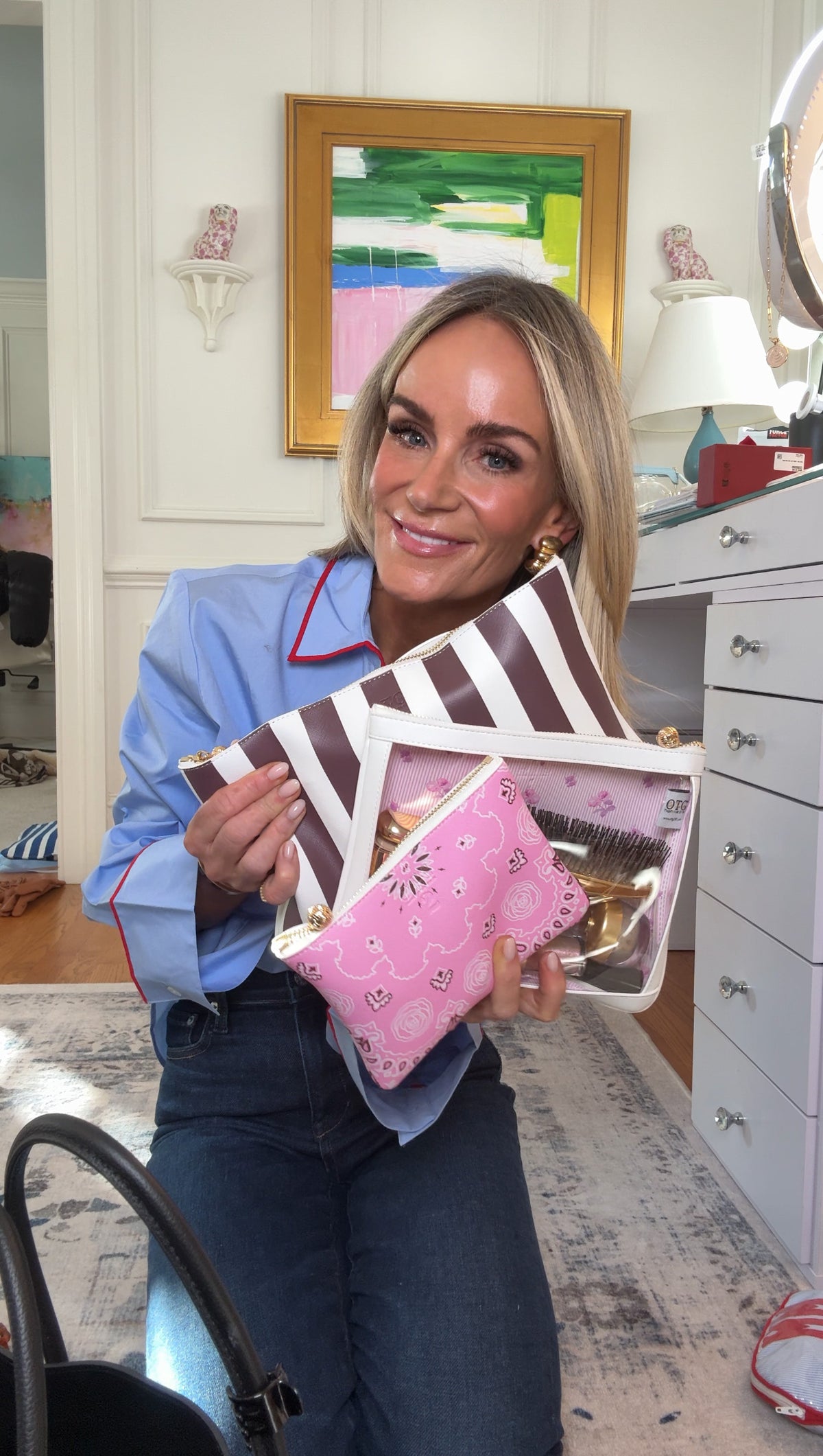 Meeghan Mullin holding OTG collaboration bags in a room with furniture and decor.