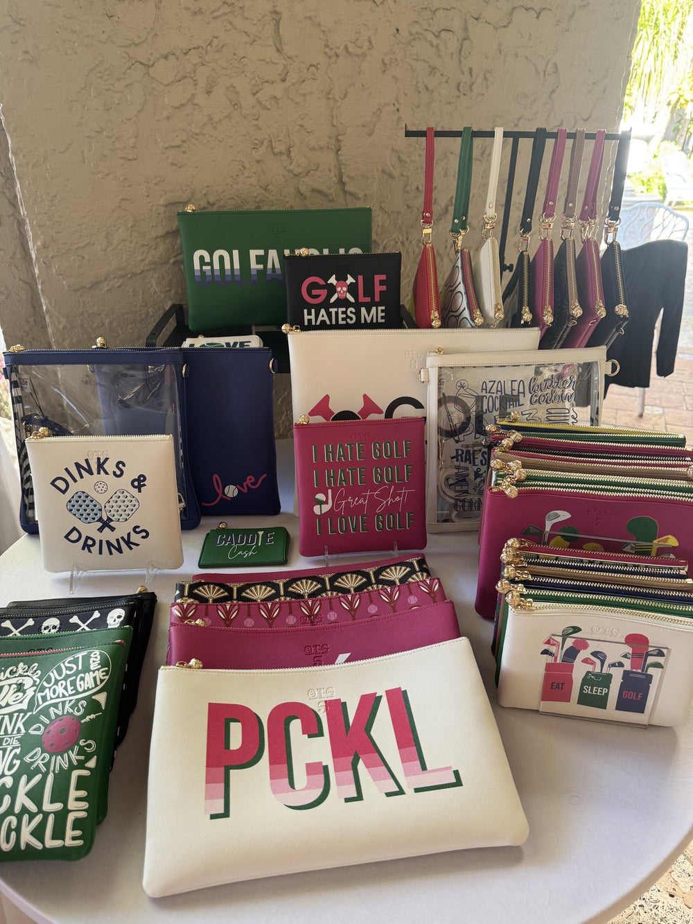 Colorful display of personalized OTG|247 pouches at a Breakers trunk show