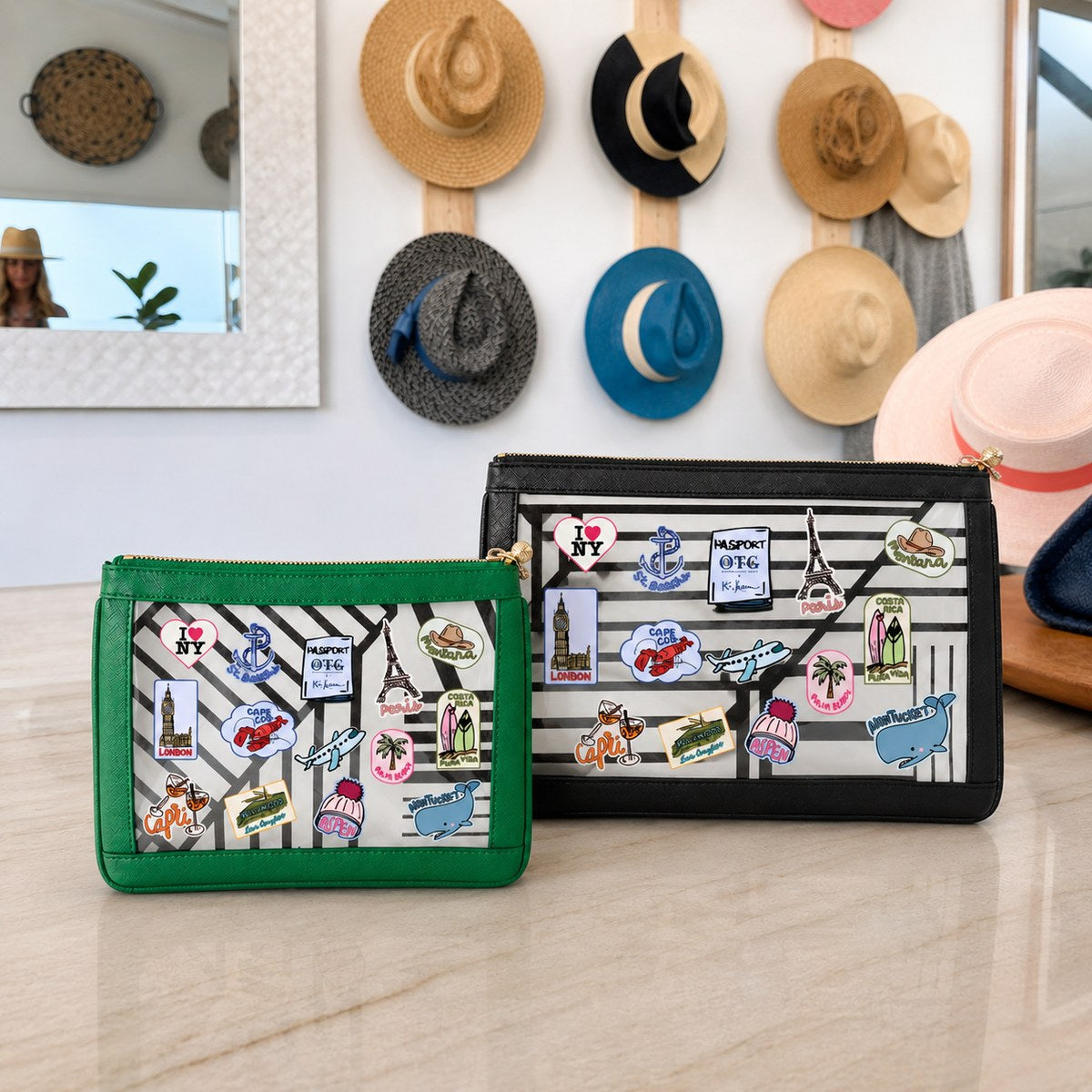 The #4 Nudie Green pouch and #5 Nudie Black clutch with Kai Lassen travel stickers, on a counter in front of a wall of hats.